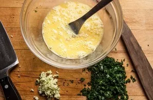 Peel and chop the garlic, beat the eggs, finely chop a few fresh herbs.