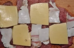 Distribute the crushed cheese and bacon over the entire surface of the meat. If desired, you can also add a little crushed garlic.