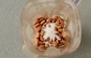 Transfer the almonds to a blender bowl, add sugar and a pinch of salt.