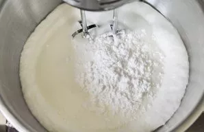 Increase the whipping speed, add lemon juice. While continuing to beat, gradually add powdered sugar.