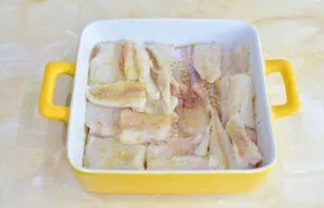 Cut the fish into small pieces and lay it out on top of the vegetables. Sprinkle with a little salt and spices.