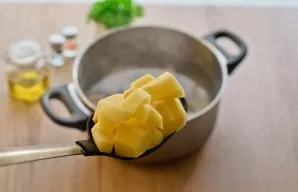 Now peel the potatoes, wash and cut into medium-sized cubes. Transfer the potatoes to the broth and cook for another 15 minutes.
