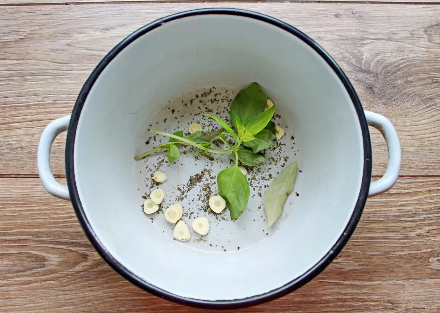 Add the bay leaf, basil sprigs and dry basil to the pot. Peel the garlic and cut it into slices, add it to the other ingredients.