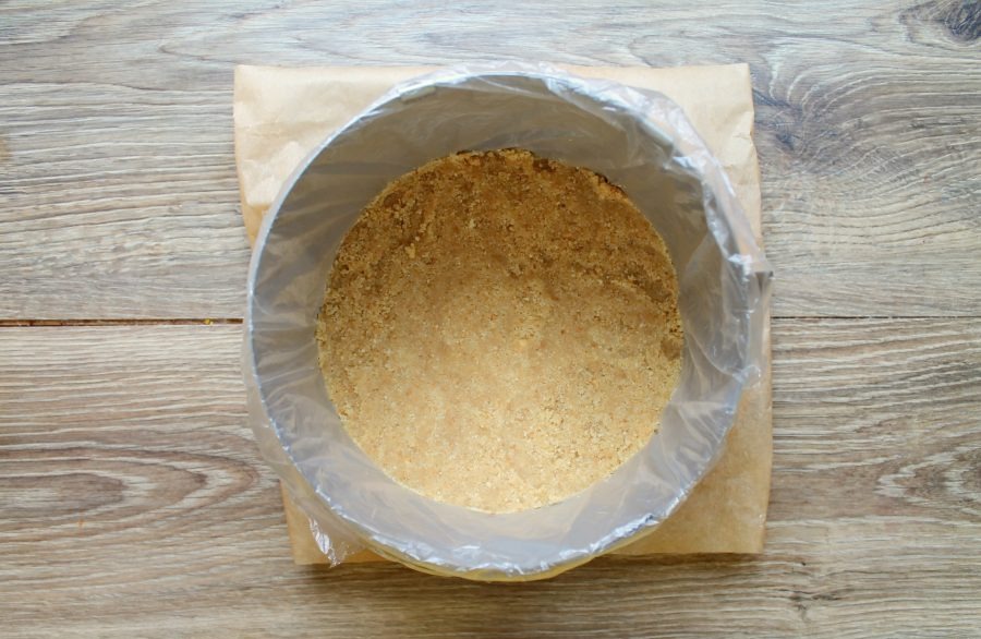 Line a cutting board with baking paper. Wrap the rolling pastry ring in cling film and place it on the paper. Transfer the cookie crumbs ...