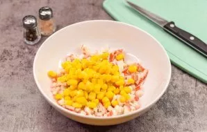 Open the canned corn and drain the juice. Put the corn in a bowl with crab sticks.