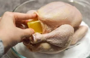 Put the hen on top of the salt. Cut the orange into four parts and put it inside the chicken. We do not rub spices into the skin of the h...