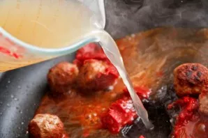 Pour in the broth, carefully dissolve the tomato paste in it.