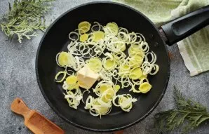 Pour vegetable oil into the pan, pour butter and heat over medium heat. Finely cut the leek into rings and, stirring, fry for 5 minutes.