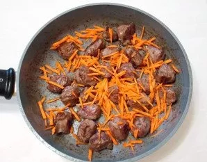 Peel the carrots and cut them into thin, long strips. Add to the pan next to the meat.
