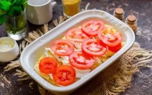 Next, coat the potatoes with sour cream. Wash and dry the tomatoes, cut into slices. Lay out slices of tomatoes on top of the potatoes.