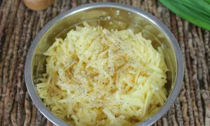 Peel the potatoes, grate and pour into a bowl. Sprinkle with ground pepper.