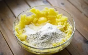 Break an egg into a slightly cooled mashed potato and add flour.