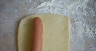 Roll out the dough into a layer about a centimeter wide. Cut the dough into sausage-sized pieces. Put the sausages on top of the dough an...