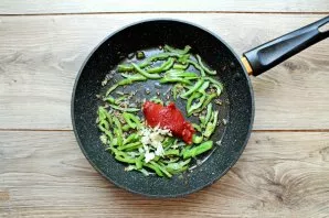 Put tomato paste and chopped garlic in the pan. Stir everything and fry for 2 minutes.