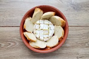Cut the baguette into pieces and lay out around the cheese. Coat the baguette and cheese with rosemary and garlic oil.