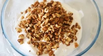 Add the prepared nuts to the protein mass, slightly leaving for decoration, and gently stir with a spatula or spoon.