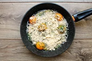 Grate the cheese on a medium grater and sprinkle the eggs with half the amount of cheese.