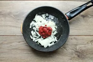 After frying the ribs, add chopped onion and tomato paste to the pan.