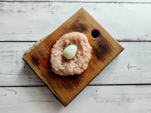 Take a small piece of minced meat, put a quail egg in the middle.