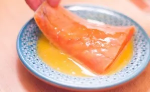 Dip a piece of salmon in an egg.