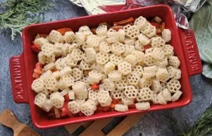 Add boiled pasta to the form with vegetables, sprinkle with dry herbs and mix.