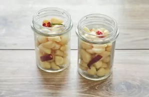 In hot jars, add garlic with chopped chilli.