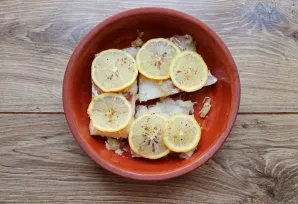 Cut the lemon into slices and spread over the fish, sprinkle with pepper.