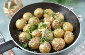 Remove the baking tray from the oven again and, if the potatoes are cooked, pierce the potatoes with a knife, then add chopped garlic, di...