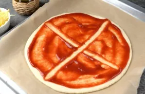 Lightly dust the baking paper with flour and roll out a thin circle about 30 centimeters in diameter. Spread tomato sauce on top, divide ...