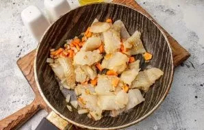 Fry onions and carrots in vegetable oil in a frying pan until tender, add pieces of fish and fry together for a couple more minutes.