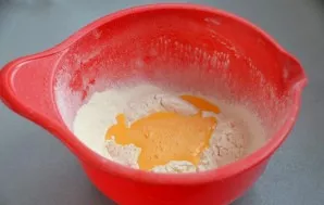 Pour the beaten eggs into the flour, mix.