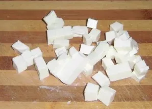 Cut the processed cheese into small cubes. If desired, you can also add 1-2 cloves of garlic to the sauce.