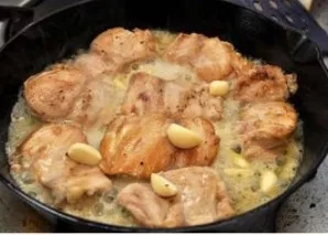 Then add the peeled garlic cloves to the fried chicken and pour everything with wine. Heat until the wine evaporates in half.