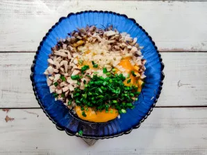 Add eggs to the chicken with mushrooms, add garlic and finely chopped greens.