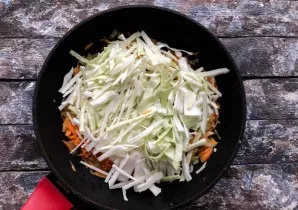 Add half of the finely chopped cabbage to the onion and carrots, mix well and simmer for 15 minutes under the lid.