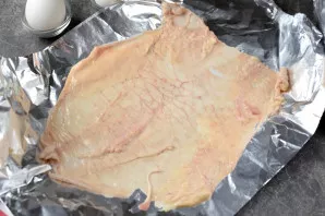 Fold the foil in half, put the skin of the chicken breast on it, salt it lightly and pepper it.