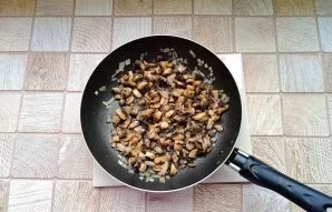Prepare the filling. Peel the mushrooms and onions, wash them and chop them finely. Put in a pan and fry in sunflower oil.