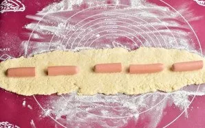 Roll out the dough first, then add the sausages cut in half.