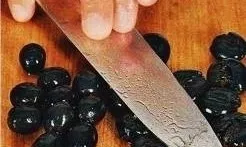 Crush the olives with the flat side of the knife and remove the dice.