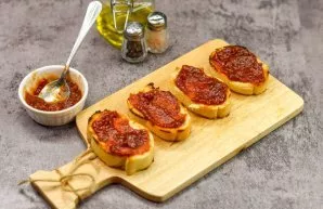 Coat the slices of the baguette with tomato sauce. Choose a rich, tasty sauce with basil and herbs.