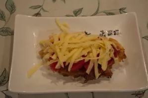 Then put a piece of sliced tomato on each baked piece. Sprinkle with grated cheese. Put in the oven until the cheese melts.