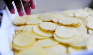 Cut the potatoes into slices 3 mm thick. Put 1/3 of the potatoes in a greased container.