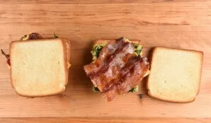 Fry the bread in a toaster or pan until browned. Then coat the two pieces with sauce, put after that an egg, a piece of cheese and bacon.