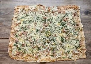 Sprinkle grated hard cheese on top in an even layer.