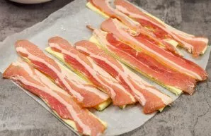 Put a strip of bacon on each piece of dough.