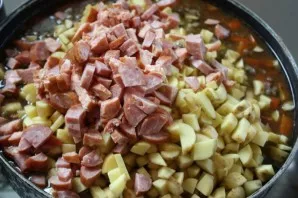 While the lentils are boiling, chop the potatoes and sausages. After the time specified in the previous step, add everything that is crus...