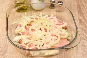 Peel and wash the onion, cut into half rings. Put half an onion on top of the meat.