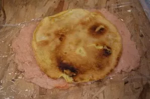 Put the omelet on a layer of mincemeat. Using a film, roll everything into a roll.