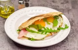 Add eggs, ham, cheese, and rukol to the pita. Pita with an egg is ready.
