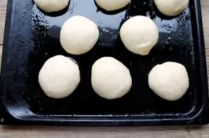 Divide the dough into equal pieces and roll it into balls. Lay them out on a greased baking sheet, leaving gaps. Cover the future pastrie...